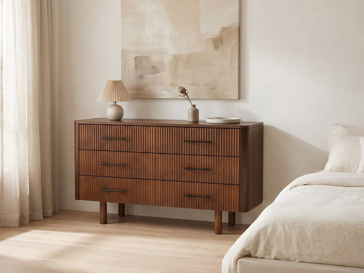 Badia 56-Inch Walnut-Finish 6-Drawer Dresser against a plaster wall under an abstract canvas in a bright bedroom