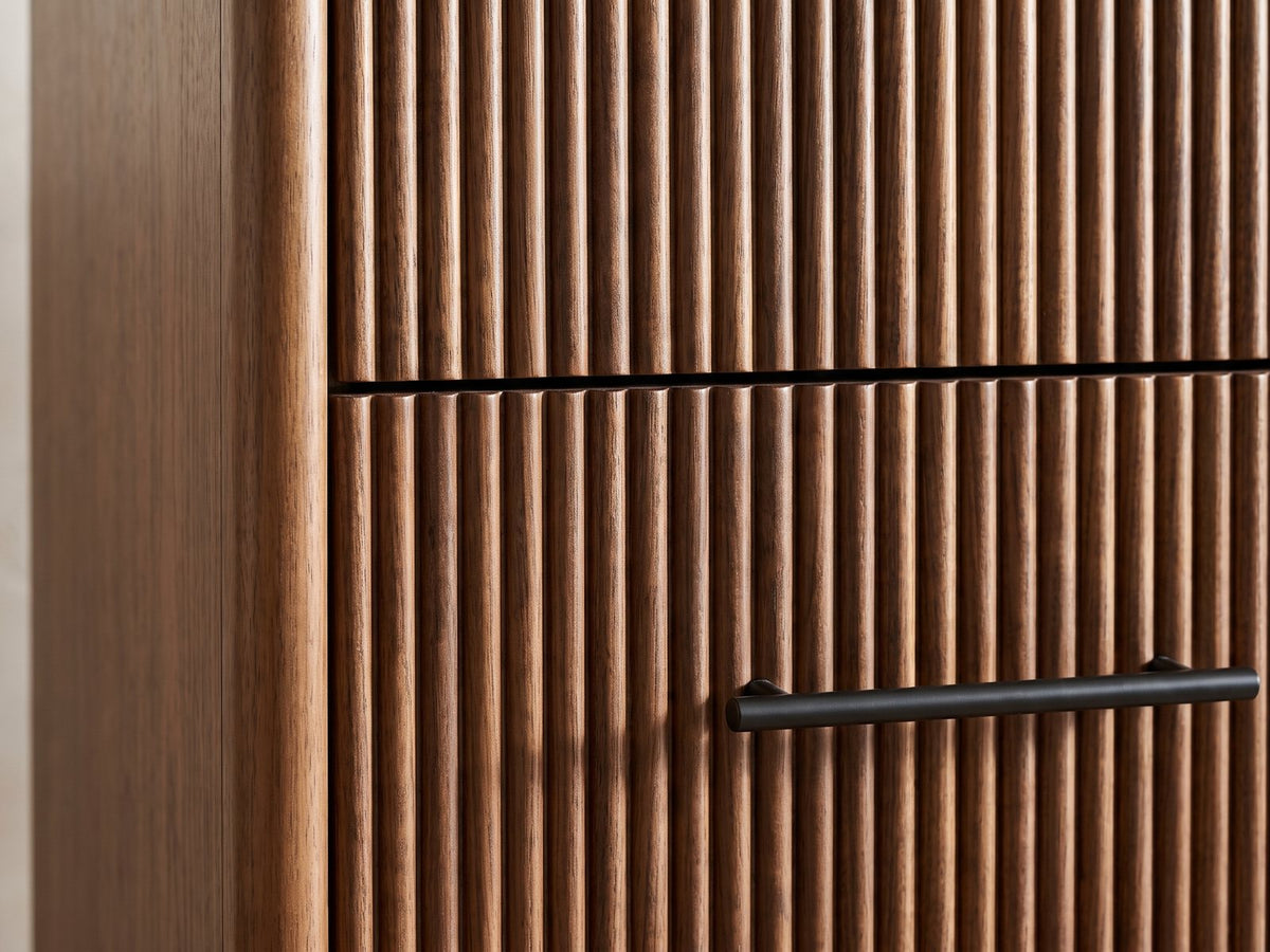 Close-up of the Badia 56-Inch Walnut-Finish 6-Drawer Dresser: the reeded walnut-finish drawer fronts beside the rounded end of the case