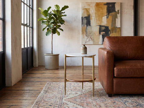 Badolato Marble and Acacia Two-Tier Side Table beside a leather sofa in an industrial loft
