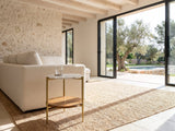 Badolato Marble and Acacia Two-Tier Side Table beside a linen sofa in a poolside villa