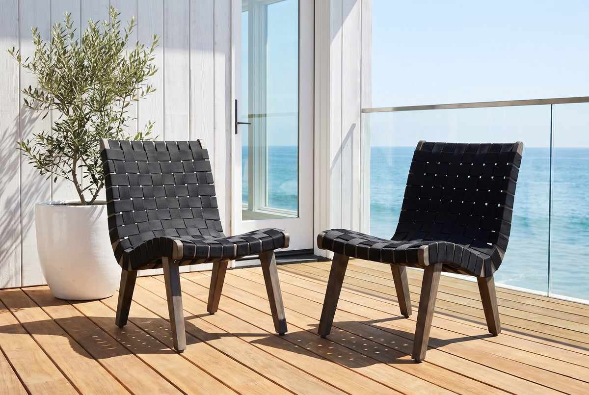 Two Bagheria lounge chairs on honey teak decking at an ocean-view house in Laguna Beach, a whitewashed board wall, a glass door and a glass rail with the Pacific behind (plant not included)