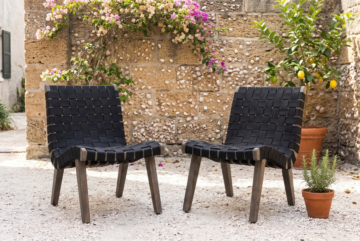 Two Bagheria lounge chairs on crushed shell in a St. Augustine courtyard, a coquina stone wall, bougainvillea and a lemon tree behind (plants not included)