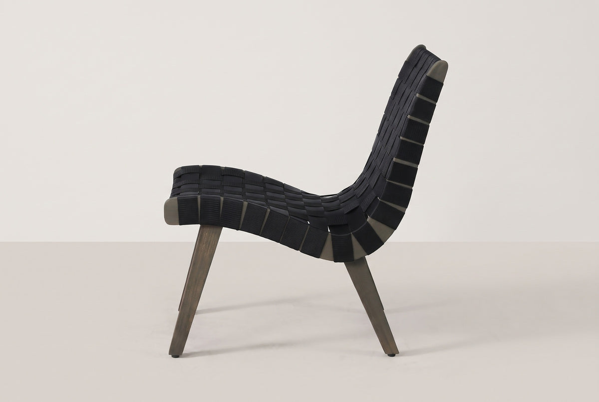 One Bagheria chair in straight side view: the curved acacia side rail, the strap ends wrapped round it and two splayed legs