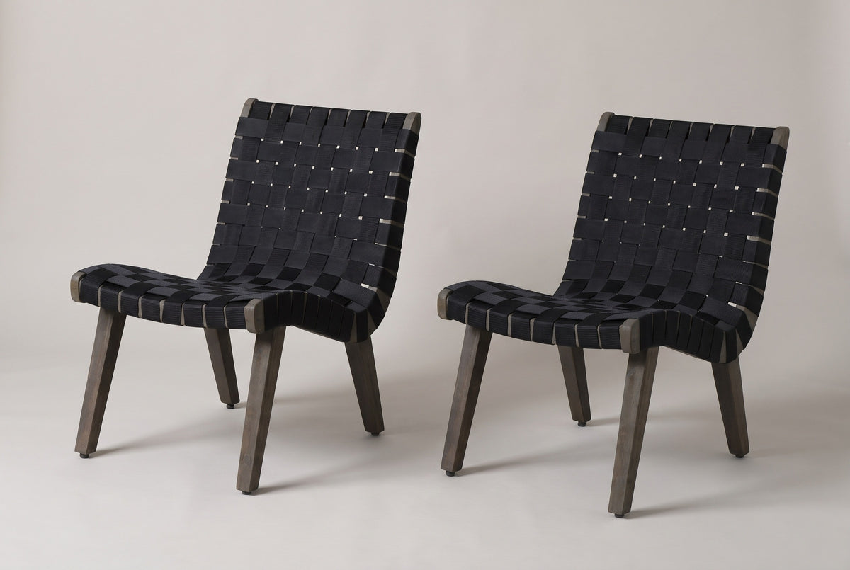 The pair of Bagheria outdoor lounge chairs in grey-brown acacia with black woven rope straps, three-quarter view on a light studio backdrop