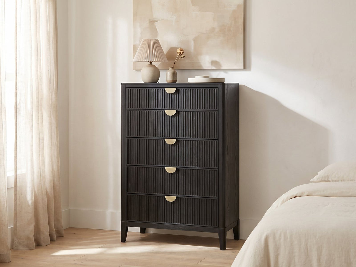 Bardolino 36-Inch Black Fluted 5-Drawer Chest against a plaster wall under an abstract canvas in a bright bedroom