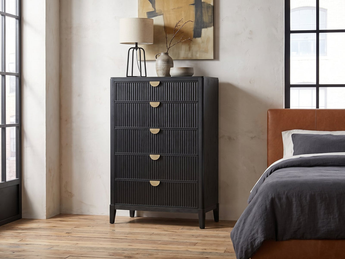 Bardolino 36-Inch Black Fluted 5-Drawer Chest against a plaster wall in an industrial loft bedroom