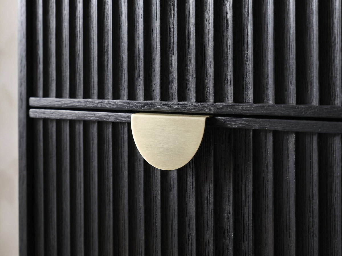 Close-up of the Bardolino 36-Inch Black Fluted 5-Drawer Chest: the brass-finish half-moon pull on the black fluted drawers