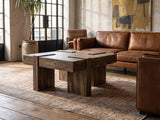 Barga Solid Sheesham Coffee Table seen from the side, on a vintage rug in front of a leather sofa in an industrial loft