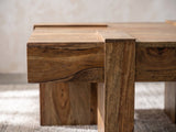 Close-up of the Barga Solid Sheesham Coffee Table: a sheesham slab leg rising flush through the thick plank edge
