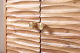 The left seam of the Barile sideboard: two small brushed-brass knobs at the wavy line between two carved doors