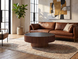 Barolo 35-Inch Round Black Sintered Stone Slatted Drum Coffee Table seen from the side, on a vintage rug in front of a leather sofa in an industrial loft