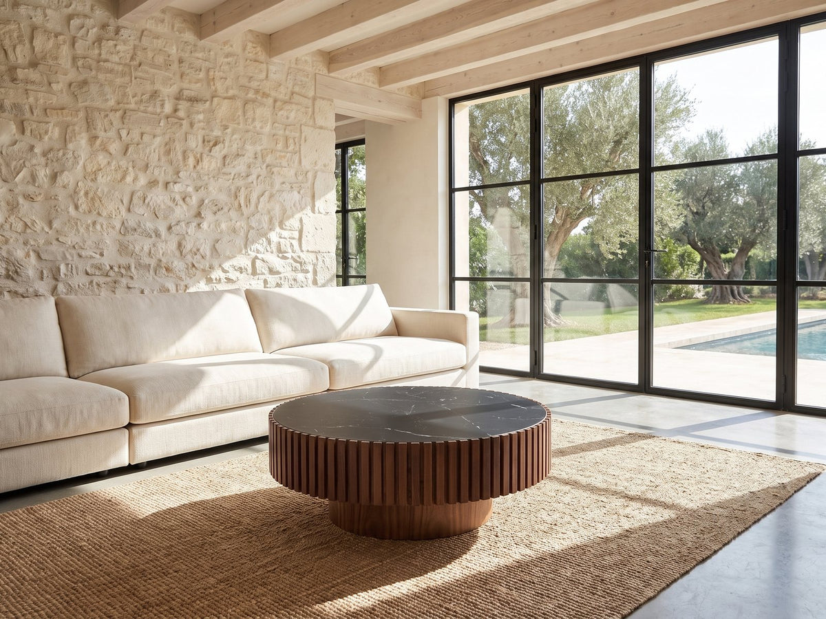 Barolo 35-Inch Round Black Sintered Stone Slatted Drum Coffee Table on a jute rug in front of a linen sofa in a poolside villa