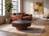Barolo 35-Inch Round Black Sintered Stone Slatted Drum Coffee Table on a vintage rug in front of a leather sofa in an industrial loft
