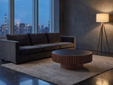 Barolo 35-Inch Round Black Sintered Stone Slatted Drum Coffee Table on a wool rug in front of a velvet sofa in a city penthouse at blue hour