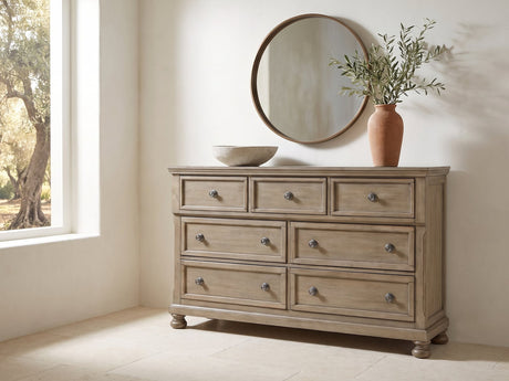 Bassano 65-Inch Wire-Brushed Driftwood Gray 7-Drawer Dresser under a round bronze mirror in a villa bedroom