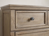 Close-up of the Bassano 65-Inch Wire-Brushed Driftwood Gray 7-Drawer Dresser: an antique pewter ring knob on a framed drawer front in wire-brushed gray birch