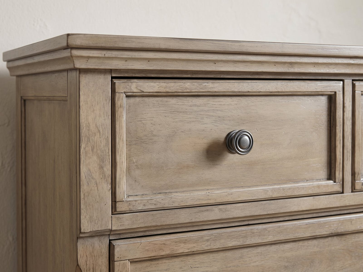 Close-up of the Bassano 65-Inch Wire-Brushed Driftwood Gray 7-Drawer Dresser: an antique pewter ring knob on a framed drawer front in wire-brushed gray birch