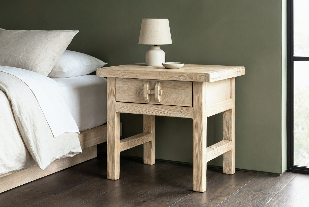 Baunei reclaimed elm nightstand with a ceramic lamp beside a low bed in a Big Sur bedroom with a deep olive-green wall and dark oak floor