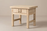 The Baunei one-drawer nightstand in pale reclaimed elm with a carved wooden pull, three-quarter view on a light studio backdrop