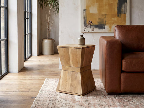 Belmonte Mango Wood Hourglass Side Table beside a leather sofa in an industrial loft