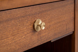 The Berchidda drawer front in walnut veneer with its round brass-tone knob on a ribbed sunburst rosette