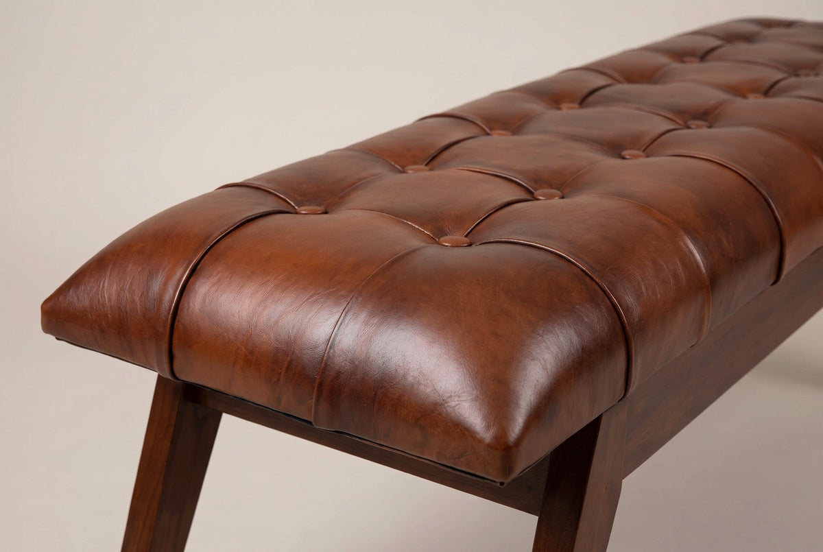 One end of the Bevagna cushion: the rounded end corner of the cognac leather, the seams and two rows of buttons receding along the top, and the walnut-brown apron below