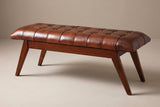 The Bevagna bench with its cognac leather cushion, three-quarter view on a light studio backdrop
