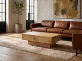 Biella 43-Inch Rectangular Burl Wood Veneer Coffee Table on a vintage rug in front of a leather sofa in an industrial loft