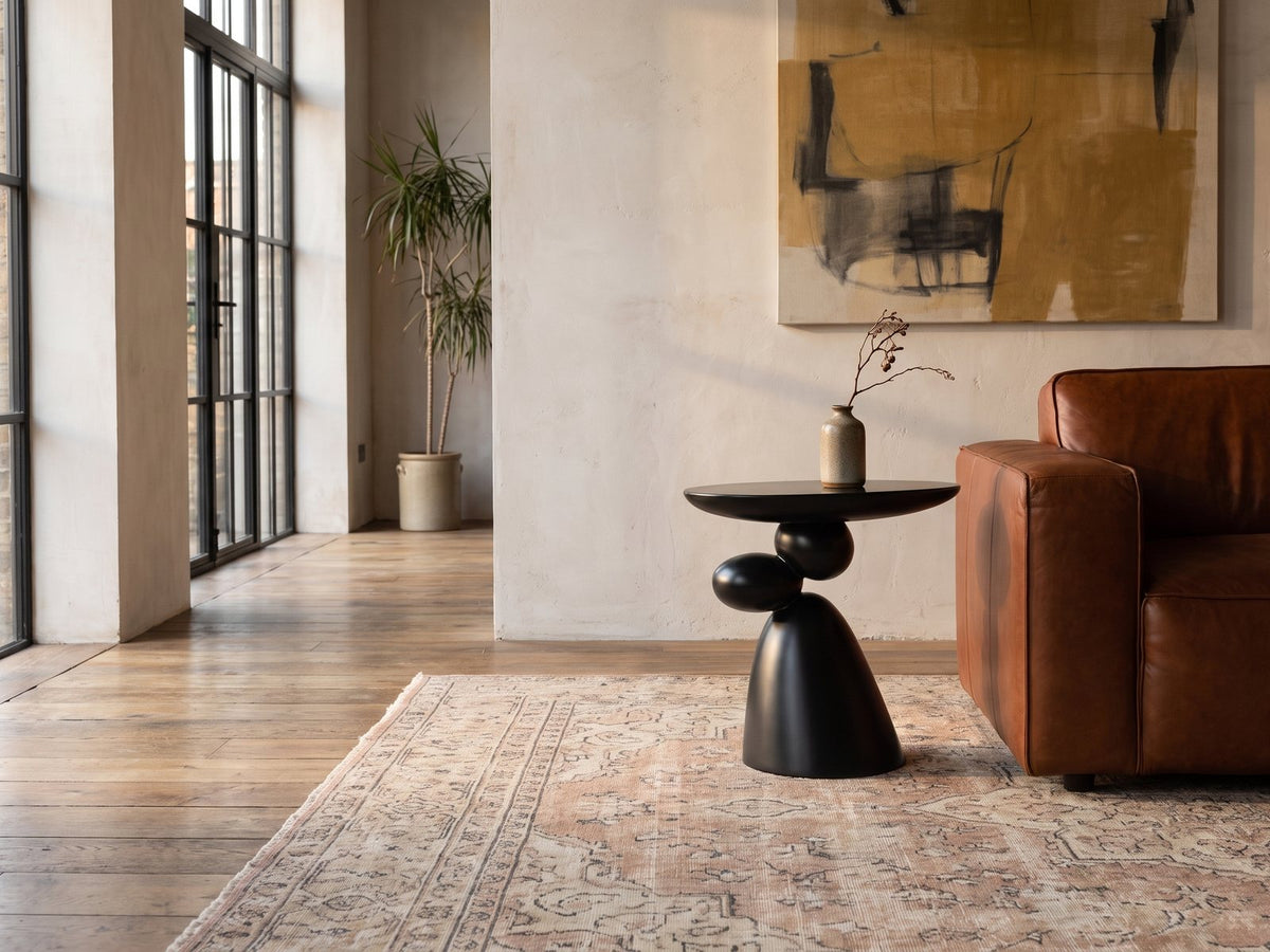 Bitetto Black Fiberglass Stacked Pebble Side Table beside a leather sofa in an industrial loft