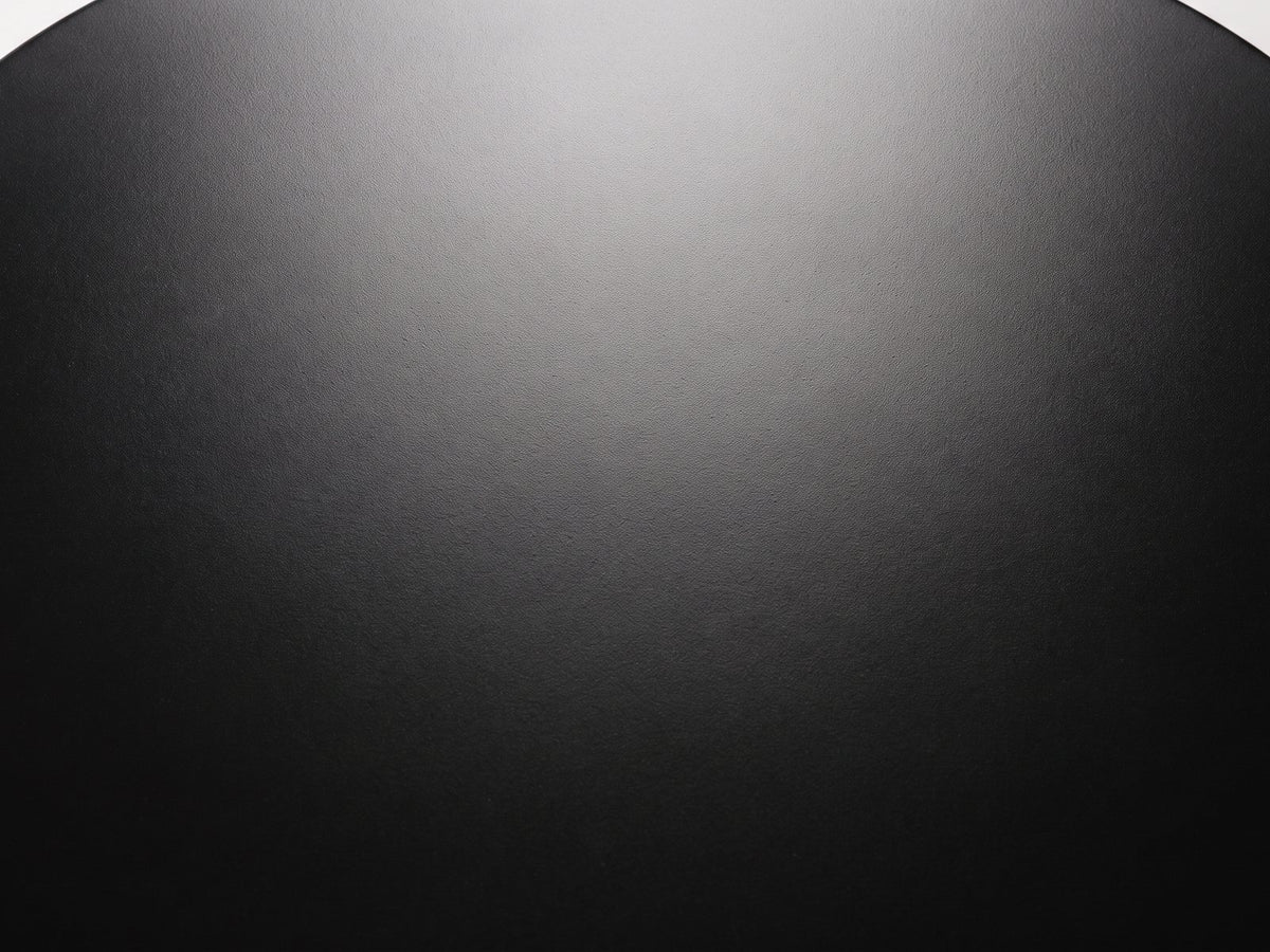 Close-up of the Bitetto Black Fiberglass Stacked Pebble Side Table: the smooth matte black finish of the oval top