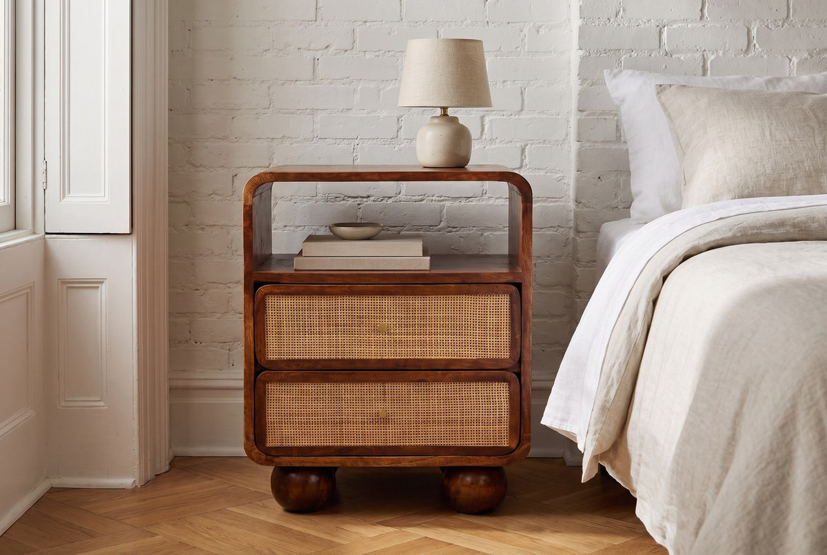 Bitti chestnut mango and cane nightstand against a white-painted brick wall in a Brooklyn brownstone bedroom with a herringbone oak floor
