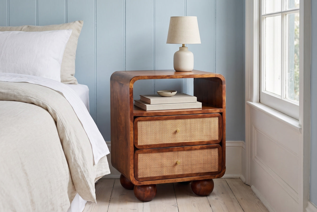 Bitti chestnut mango and cane nightstand with a ceramic lamp in a Charleston bedroom with a powder-blue paneled wall and whitewashed pine floors