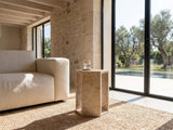 Bojano Rosa Marble Hexagon Side Table beside a linen sofa in a poolside villa
