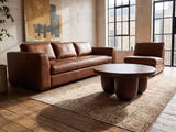 Bolgheri Sculpted Mango Coffee Table on a vintage rug in front of a leather sofa in an industrial loft