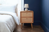 Bono oak and cane nightstand against a deep navy wall in a Brooklyn brownstone bedroom with a herringbone parquet floor