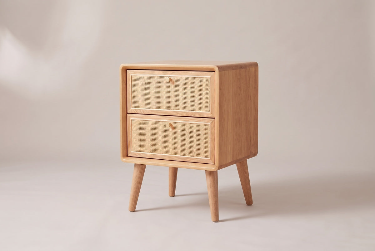 The Bono two-drawer nightstand in light oak with woven cane drawer fronts and gold knobs, three-quarter view on a light studio backdrop