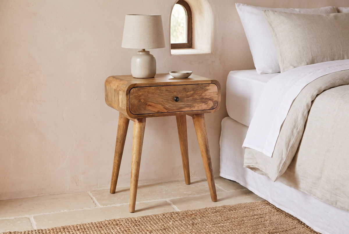 Bonorva light mango nightstand against a blush lime plaster wall in a Santa Barbara bedroom with stone tiles and a jute rug