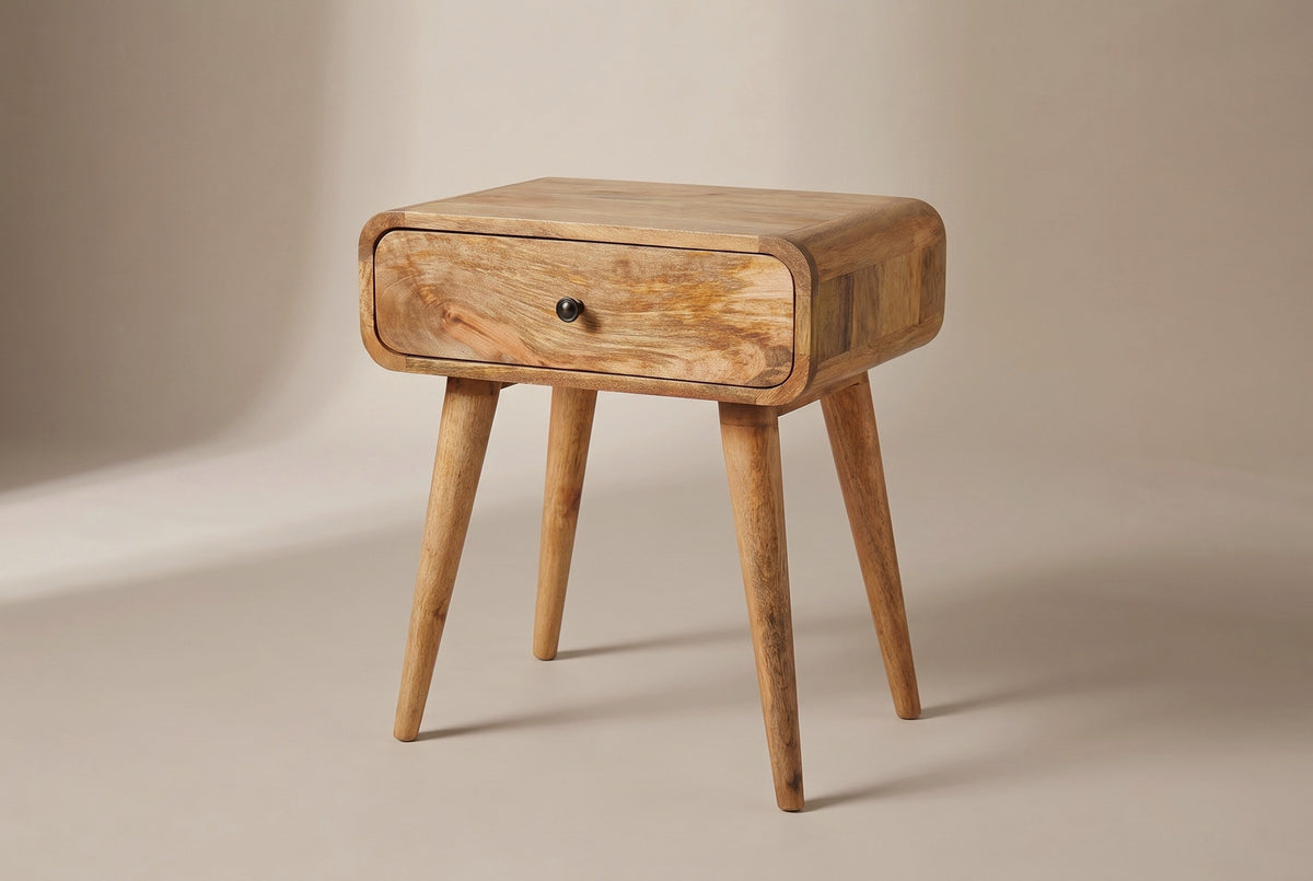 The Bonorva one-drawer nightstand in light mango with a dark round knob, rounded corners and four splayed round legs, three-quarter view on a light studio backdrop