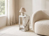 Bovino White Marble Hexagon Side Table with a lamp and a ceramic bowl beside a cream boucle armchair in a bright plaster room