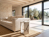 Bovino White Marble Hexagon Side Table beside a linen sofa in a poolside villa