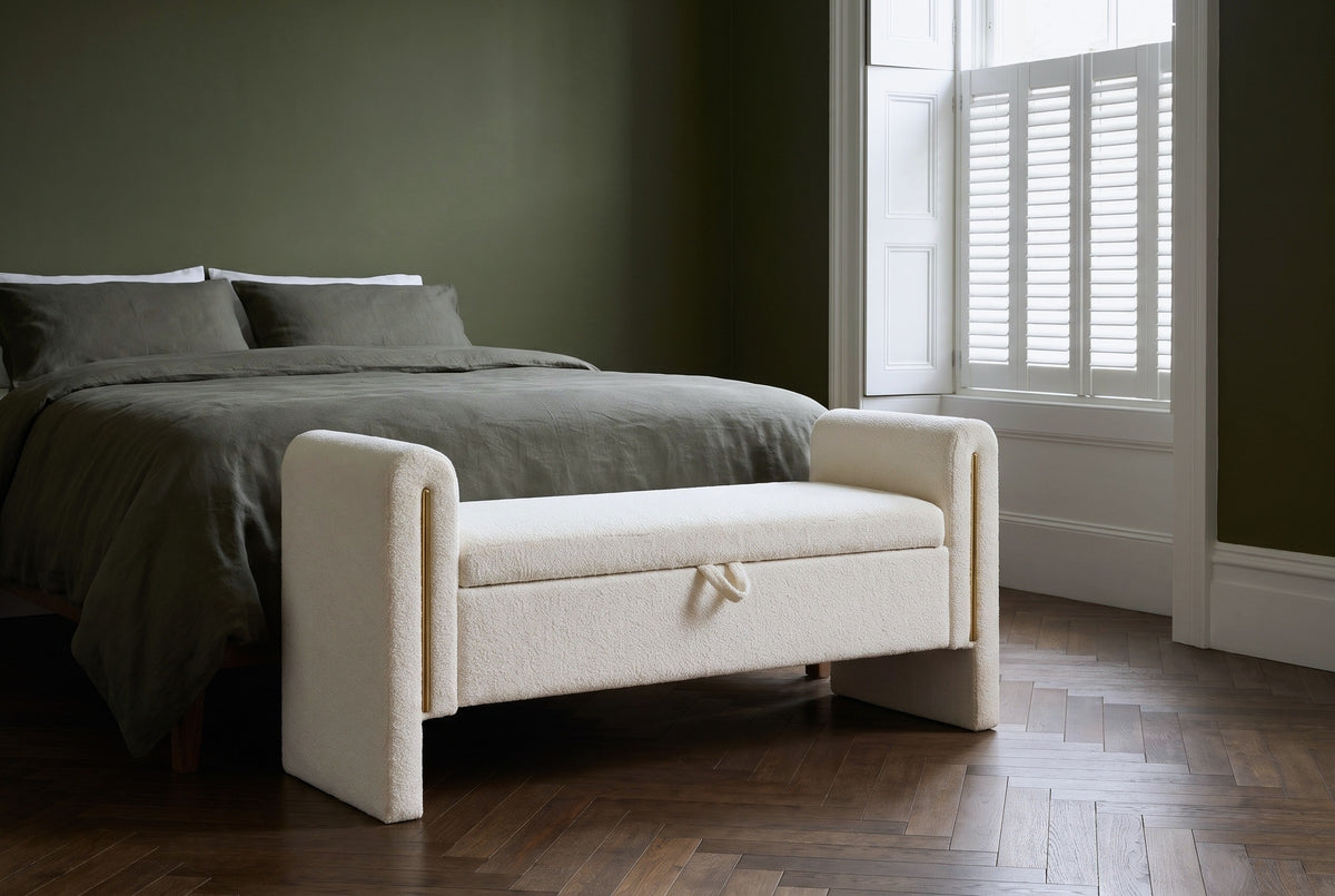 Bracciano cream teddy bench at the foot of a bed with olive linen bedding in a Brooklyn brownstone bedroom with a deep olive green wall and a dark herringbone floor (bed not included)