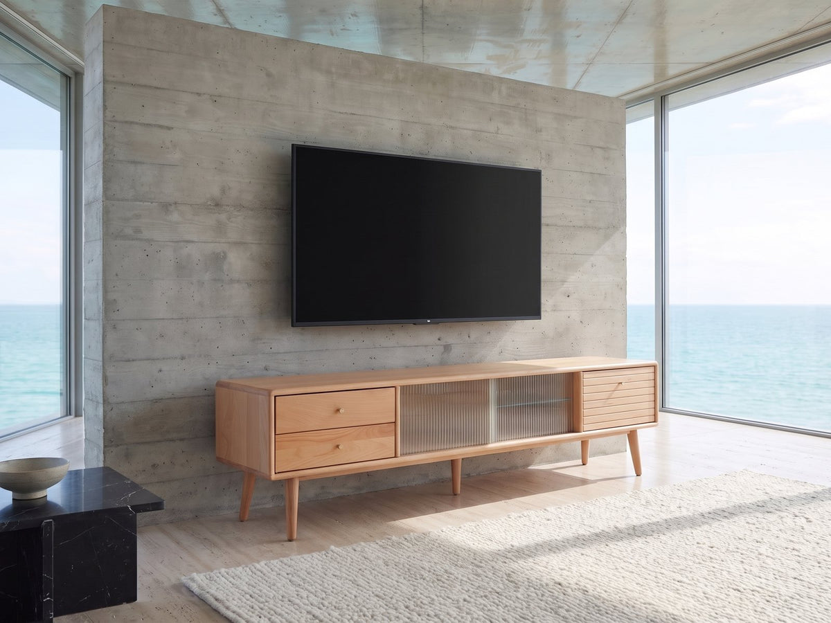 Bressanone Solid Beech Media Console seen from the side, under a wall-mounted screen in an oceanfront glass house