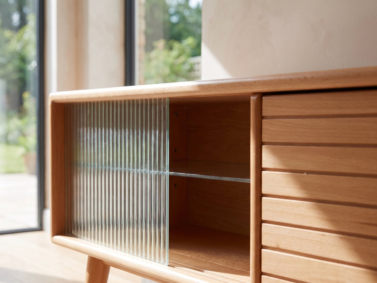 Close-up of the Bressanone Solid Beech Media Console: the reeded glass sliding door and the slatted beech door with its brass knob beside it
