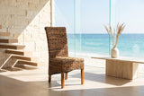Briatico High-Back Woven Natural Fiber Dining Chair in an oceanfront glass house