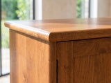 Close-up of the Brisighella Mid-Century Media Console: the top corner of the console: the solid wood top edge and the door below with its slim black pull