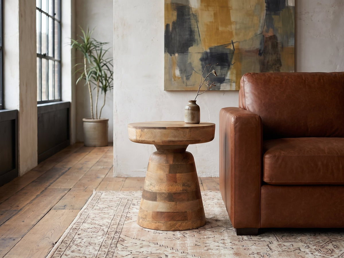 Bronte Solid Mango Pedestal Side Table beside a leather sofa in an industrial loft