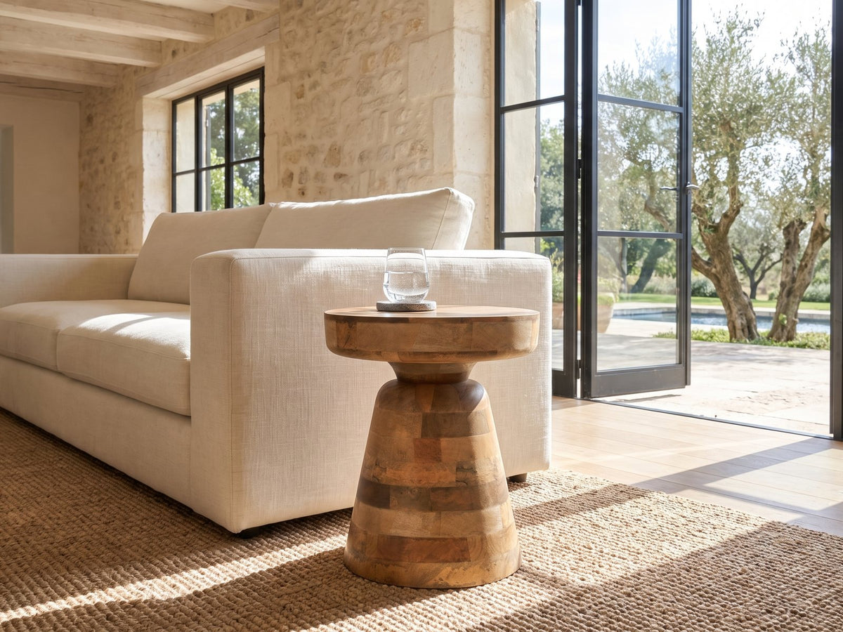 Bronte Solid Mango Pedestal Side Table beside a linen sofa in a poolside villa