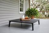 Brucoli black aluminum coffee table on a grey-painted porch floor in Beaufort, South Carolina, grey siding, a fern and live oaks behind (tray, pitcher and plant not included)