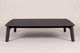 The Brucoli coffee table seen from the front: the thin black top with rounded corners on four tapered legs