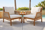 Two Buccheri club chairs on a concrete pool terrace in Sarasota, a honey coquina stone wall, sea grape and palms behind (side table not included)